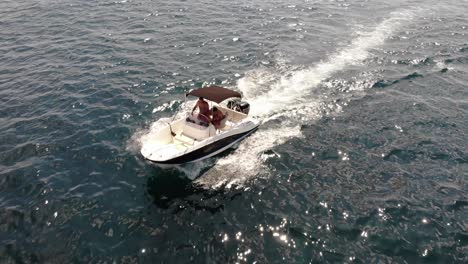 Two-men-enjoy-motorboat-pleasurecraft-in-tracking-aerial,-clear-water