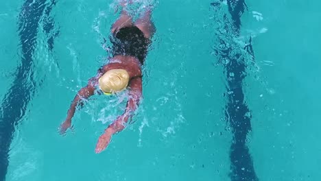 Overhead-Kamerafahrt-Einer-Athletischen-Frau,-Die-In-Einem-Pool-Schwimmt