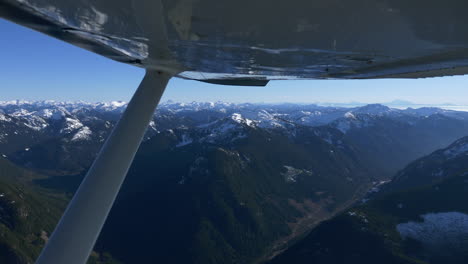 Vista-Panorámica-De-Exuberantes-Montañas-Cubiertas-De-Nieve-Desde-La-Ventana-Del-Avión-Cessna-172-En-Vuelo-Desde-Vancouver-A-Pemberton-En-Columbia-Británica,-Canadá