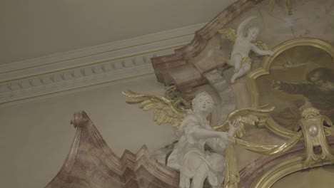 Sculptures-of-angels-with-golden-wings-on-a-baroque-altar-in-a-church,-picture-of-god-in-the-middle