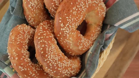 Golden-Bagels-with-Sesame-Seeds-Spin-on-Table-in-Woven-Basket,-Top-Down-View