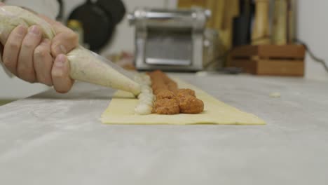 Chef-adds-mushroom-sauce-onto-lasagna-dough