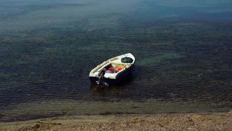 Barco-Estacionado-En-La-Orilla-Del-Mar-Con-Aguas-Tranquilas-Cerca-Del-Pueblo-De-Pescadores-Mediterráneos