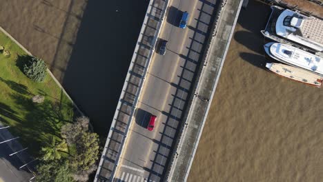 Aerial-birds-eye-shot-of-cars-crossing-small-bridge-during-sunny-day-in-Tigre,Argentina