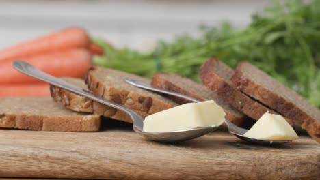 Wooden-cutting-board-with-slices-of-wholemeal-bread-and-two-servings-of-butter