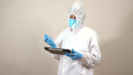 nurse-dressed-in-ppe-suit-consulting-treatments-on-the-tablet-and-gesturing