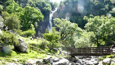 People-trekking-Aber-falls-Snowdonia-mountain-Welsh-national-park-waterfall-footbridge