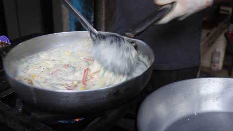 Professional-chef-prepares-white-sauce-Pasta-at-a-street-food-shop-at-Chat-Gali-in-Agra,-India-on-07-March-2021