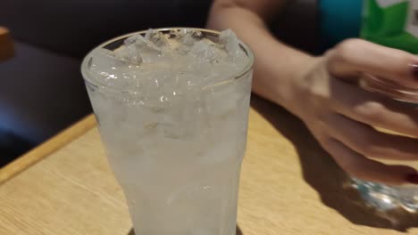 Frauenhand-Gießt-Trinkwasser-In-Das-Glas-Voller-Eis