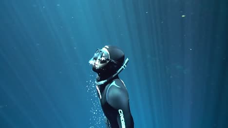 freediving-upward-from-sea-bottom-in-clear-blue-water-penetrated-by-sunlight-rays,-summer-lifestyle