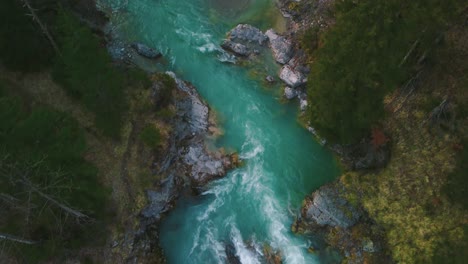 Aerial-flight-above-a-scenic-and-idyllic-mountain-river-waterfall-canyon-with-fresh-blue-water-in-the-Bavarian-Austrian-alps,-flowing-down-a-beautiful-riverbed-along-trees,-forest-and-rocks-by-drone