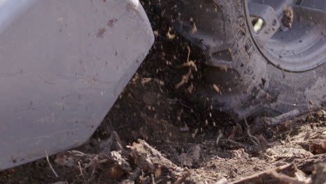 Blades-and-wheel-of-a-rototiller-throw-soil,-agriculture,-slow-motion-close-up