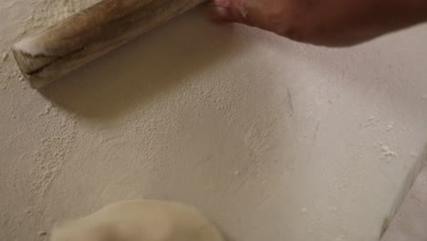 Close-up-shot-of-a-professional-chef-using-a-small-roller-to-flatten-dumpling-dough