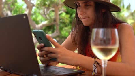 Young-woman-working-using-phone,-remote-Work-Concept,-outdoors-office-sunny-day-with-wine