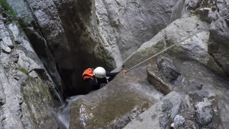 Frau-Im-Weißen-Helm-Abseilen-Wasserfall-In-Flussschlucht-Unten