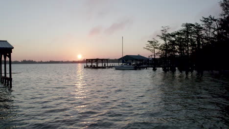 Peaceful-sunrise-over-lake-with-docks,-drone-shot