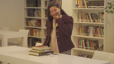 Middle-aged-woman-wearing-jacket-laughs-in-library