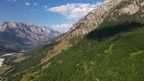 Panoramic-flight-over-beautiful-valley-of-Valbona-in-Albanian-Alps-with-green-forestry-and-sharp-mountains