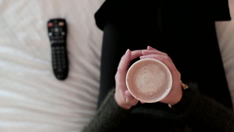 Cozy-Women-Drinking-Hot-Chocolate-Turns-On-The-TV