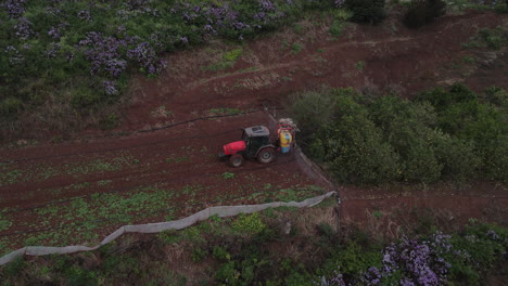 shot-of-drone-in-orbit-over-tractor-spraying,-potato-plantations