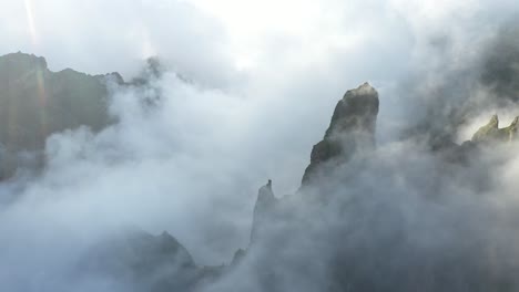 Luftaufnahme-Des-Pico-Das-Torres-Auf-Madeira-Mit-Dramatischen-Und-Wunderschönen-Wolken,-Die-Sich-Während-Des-Sonnenaufgangs-Durch-Das-Tal-Und-Die-Gipfel-Bewegen,-Wobei-Das-Sonnenlicht-Durchscheint
