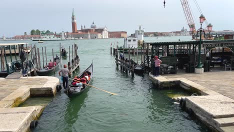 Gondolier-Steering-Gondola-with-San-Marco,-St-Mark's-Basilica-and-Campanile-in-Background
