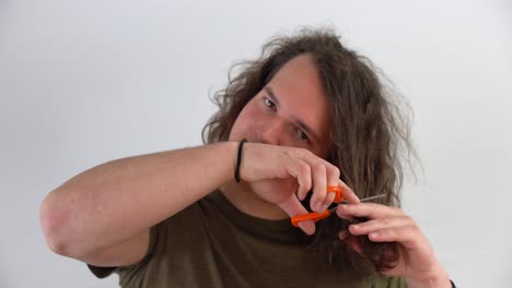 young-man-getting-ready-with-scissors-to-cut-his-own-long-hair-in-close-up-shot-with-white-background