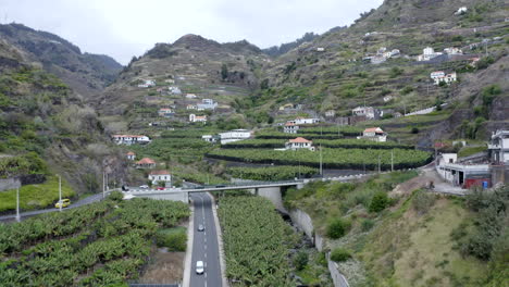 An-aerial-shot-flying-through-a-valley-in-Madeira-with-the-terraced-fields-for-growing-crops-in-Ribeira-Brava-in-the-village-of-Tabua-on-the-south-coast-of-Madeira-island,-Portugal