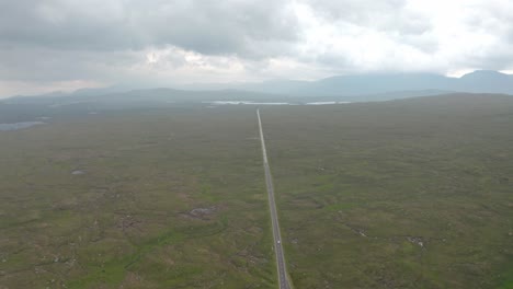 High-drone-shot-over-straight-road-through-Scottish-countryside