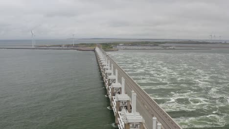 Aerial-shot-of-water-passing-through-the-Eastern-Scheldt-storm-surge-barrier-in-Zeeland,-the-Netherlands,-on-a-stormy-day