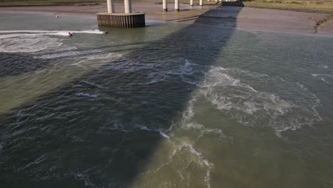 People-Riding-Jet-Skis-Under-Kingsferry-Bridge-And-Sheppey-Crossing-In-UK---panning-shot