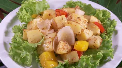 Fresh-Potato-Salad-with-Onions-and-Bell-Peppers-Decorated-with-Freshly-Cut-Lettuce-on-a-White-Plate-Spinning-with-Close-Up