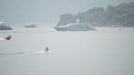 Yachts-and-speed-boats-sailing-near-coast-of-an-island-in-Corfu,-Greece
