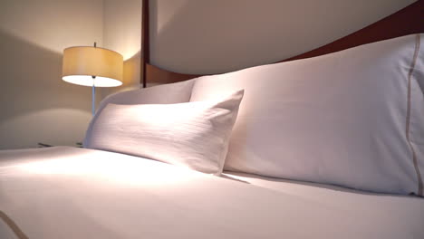 Close-up-pan-of-pillows-on-a-richly-appointed-hotel-suite-bed