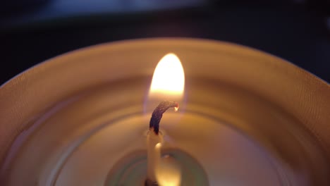 Flamme-Nahaufnahme-Makroaufnahme-Eines-Teelichtes-Brennender-Docht-Vor-Schwarzem-Hintergrund