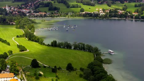The-riverbank-of-the-popular-tourism-destination-Tegernsee-with-the-zoomed-out-view-of-Gmund-in-summer-with-boats-on-the-turquoise-colored-water
