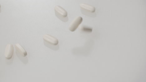 Pills-falling-on-a-white-surface-in-slow-motion