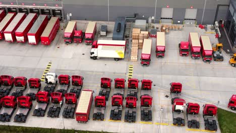 Aerial-view-rows-of-post-delivery-hub-logistics-trucks-parked-at-postal-sorting-depot-Birdseye-dolly-right