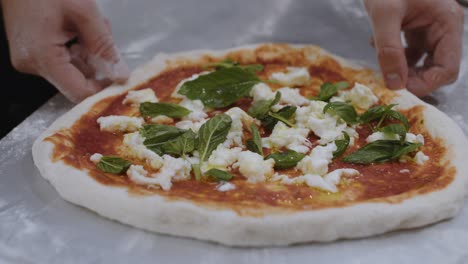Chef-slides-prepared-neapolitan-pizza-dough-with-ingredients-onto-peel-before-baking