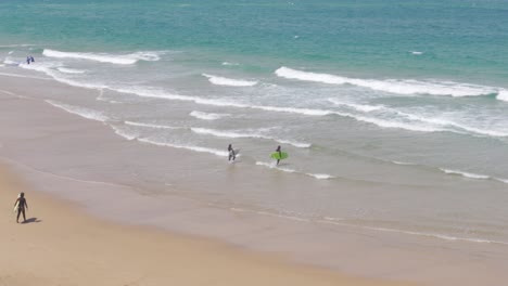 Dos-Surfistas-Entrando-Al-Agua-Con-Sus-Tablas-De-Surf-En-Praia-Do-Guincho,-Portugal