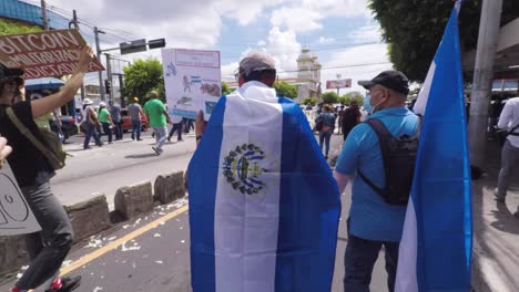 Demonstranten,-Die-Während-Des-Protestmarsches-Gegen-Die-Verwendung-Von-Bitcoin-Und-Präsident-Nayib-Bukele-Mit-Salvadorianischer-Flagge-Durch-Die-Straßen-Gingen