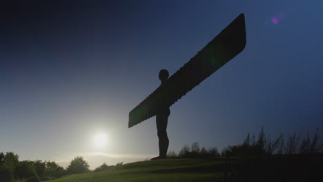 Angel-of-the-North-silhouetted-against-a-dark-blue-sky,-low-sun