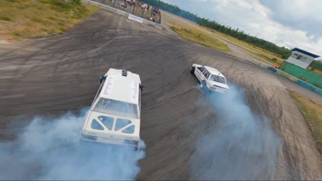 Two-Volvo-740-cars-drifting-together-in-Hultsfred-Drift-Track,-filmed-with-FPV-drone