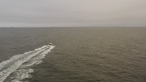 An-aerial-view-of-a-small,-white-fishing-boat-speeding-in-the-deep-Atlantic-Ocean-out-by-Long-Island,-NY