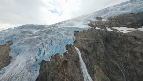 Aerial-flight-over-slowly-melting-ice-glaciers-on-mountaintop-during-hot-weather-in-nature