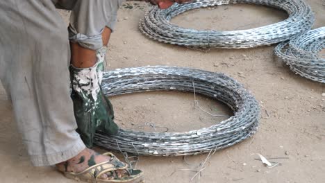 Worker-Using-Heavy-Duty-Wire-Cutters-On-Roll-Off-Barbed-Wire-On-Floor