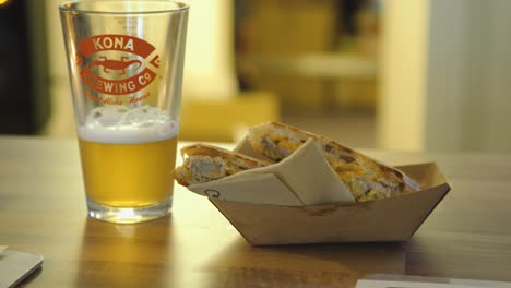 Tracking-shot-of-pint-of-beer-and-panini-sandwich-cut-in-half-with-napkin