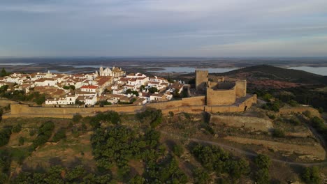 Drone-Sigue-Una-Muralla-Medieval-Alrededor-De-La-Ciudad-Del-Castillo-De-Monsaraz-Con-Paredes-Blancas-Y-Techos-De-Tejas