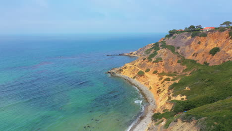 Picturesque-view-of-a-beach-with-turquoise-ocean-waves-gently-breaking-on-the-sandy-beach-at-Palos-Verdes,-California-pull-back-aerial-view