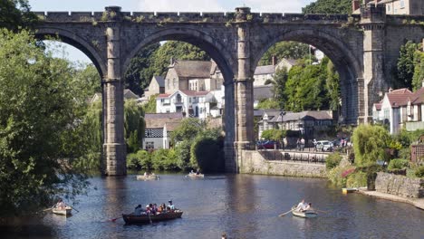 Railway-viaduct-across-river-Nidd-Knaresborough-Yorkshire-UK,-showing-people-in-rowing-boats-enjoying-themselves-on-a-sunny-day-during-summertime